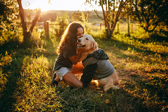 Woman with service dog outdoors at sunset, sharing a tender moment during a peaceful autumn setting. Woman with service dog outdoors at sunset, sharing a tender moment during a peaceful autumn setting.