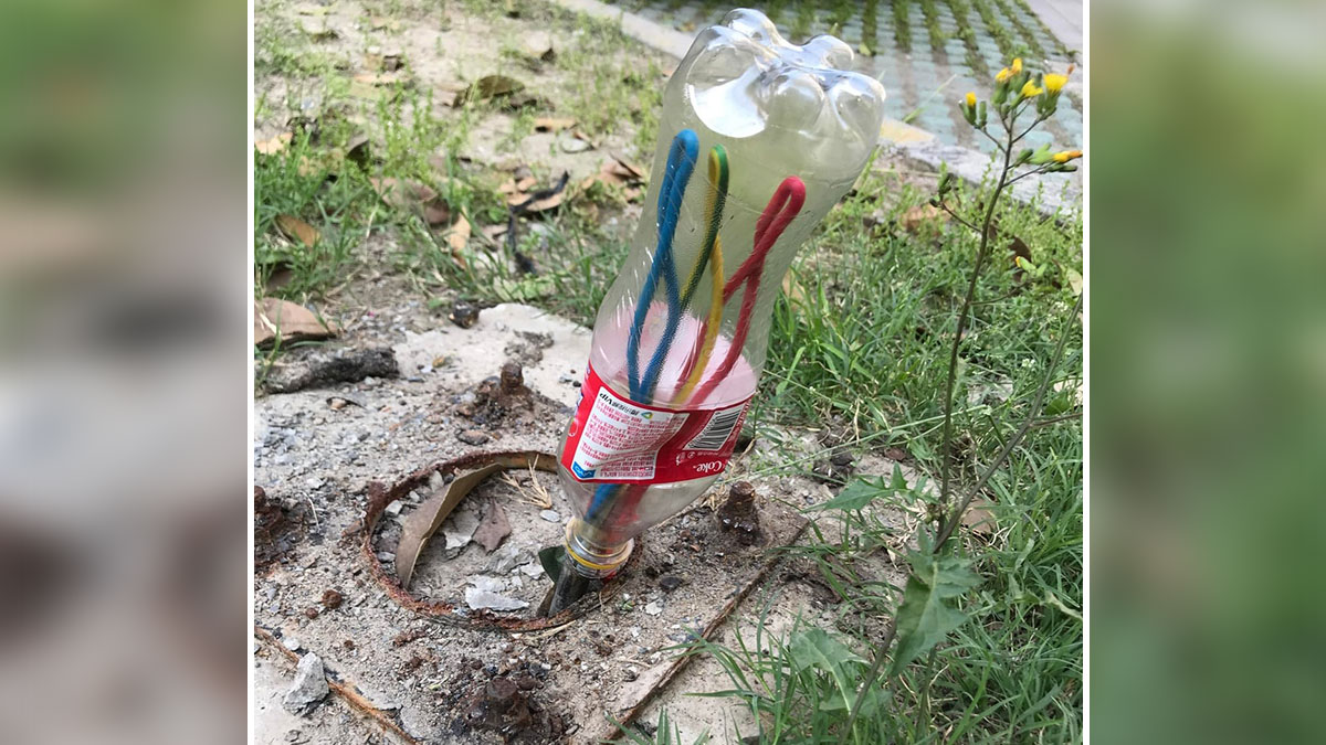 Plastic bottle makeshift cover over exposed cables in the ground, a funny example of people not even trying.