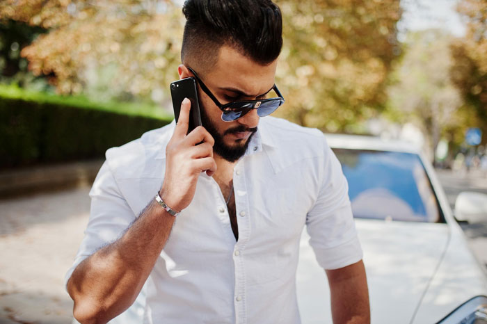 Young man in white shirt talking on phone outdoors, representing Indian grandmother demanding DNA test over baby’s skin tone. Young man in white shirt talking on phone outdoors, representing Indian grandmother demanding DNA test over baby’s skin tone.