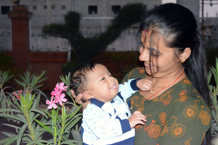 Indian grandmother holding baby, concerned about baby's pale skin, questioning DNA and parentage outside near plants. Indian grandmother holding baby, concerned about baby's pale skin, questioning DNA and parentage outside near plants.