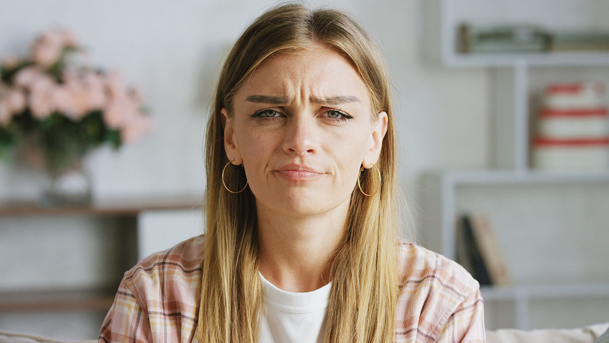 Young woman with a suspicious expression, feeling something is off during holiday with her husband and wifeu2019s friend.