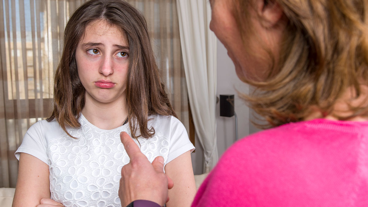 Upset 10-year-old girl listens as woman in pink discusses feeling like a single parent due to work-family conflict.