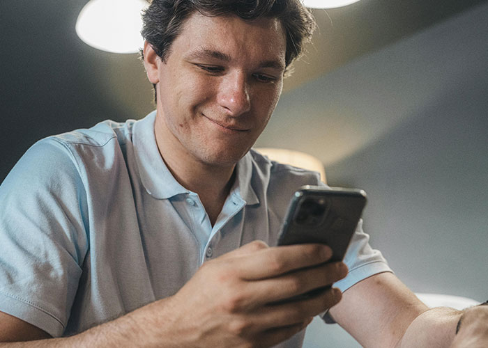 Man with a smirk looking at his phone, reflecting a husband making fun of his wife to his cheating ex-wife. Man with a smirk looking at his phone, reflecting a husband making fun of his wife to his cheating ex-wife.