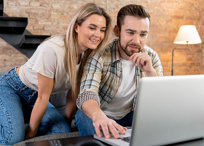 Couple investigating master's degree claim on a laptop together, woman leaning close to man in casual setting.