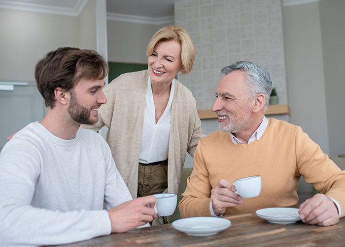 Middle-aged couple and young man having a conversation over coffee, illustrating a story about a master’s degree lie.