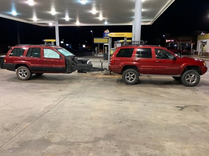 Two red SUVs modified and connected unusually at a gas station showcasing redneck engineer creativity.