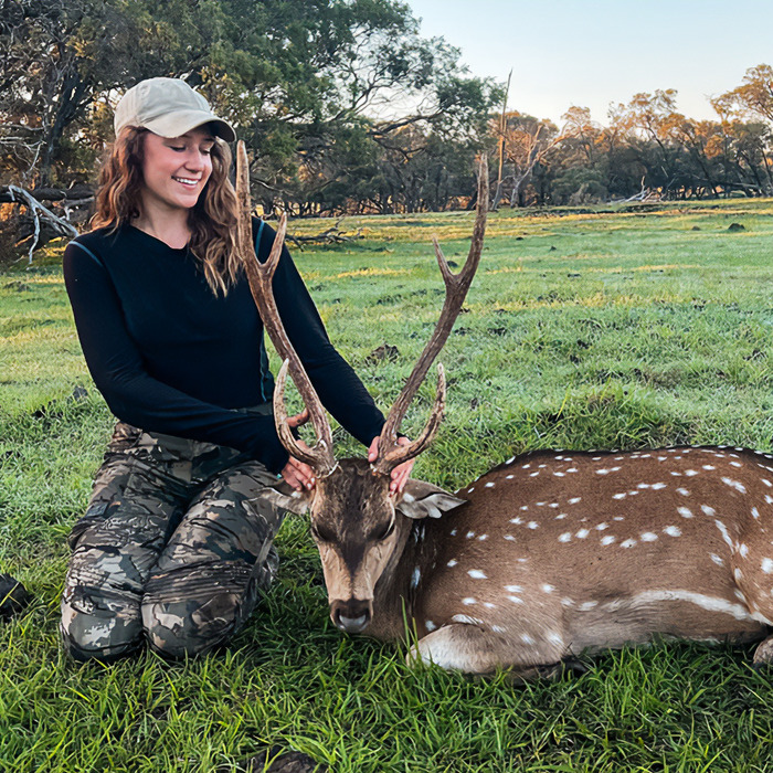 Woman kneeling on grass holding antlers of a spotted deer, symbolizing wildlife interaction and nature care. Woman kneeling on grass holding antlers of a spotted deer, symbolizing wildlife interaction and nature care.