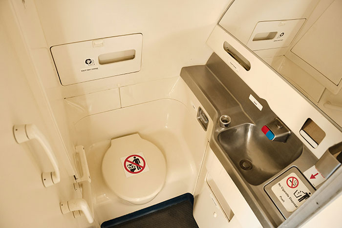 Compact airplane lavatory interior with toilet and sink, illustrating secrets about planes and flying passengers often don’t know