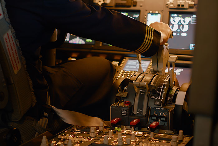 Pilot operating flight controls inside a cockpit, illustrating secrets about planes and flying for passengers.