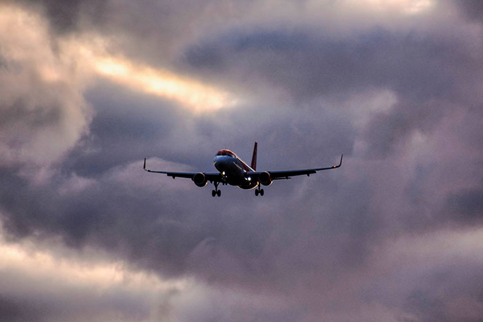 Commercial plane flying against a dramatic cloudy sky, illustrating secrets about planes and flying for passengers.