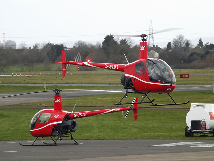 Two red helicopters on a runway, illustrating interesting secrets about planes and flying for passengers worldwide.