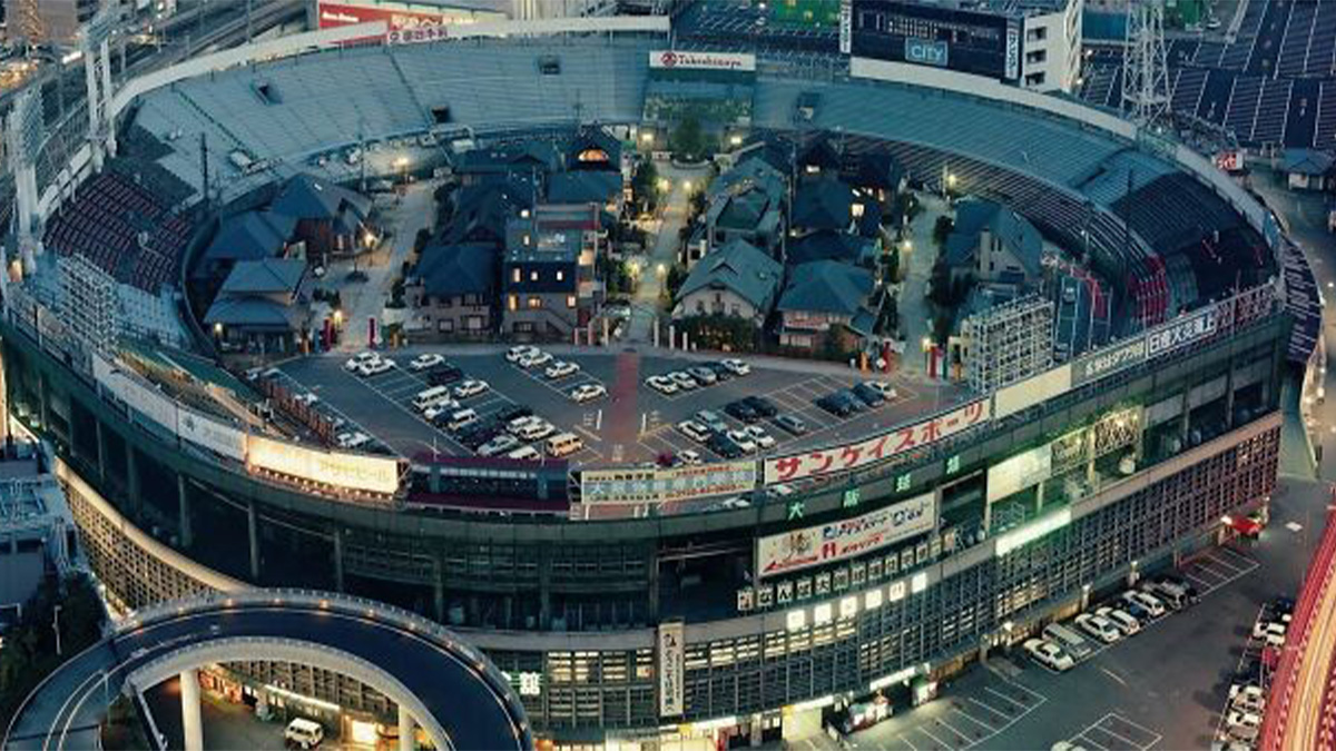 Aerial view of a stadium converted into a residential area and parking lot showing a different world perspective at dusk.