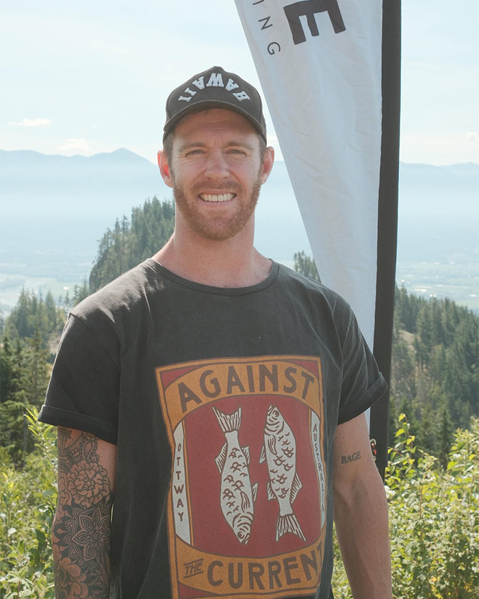Jiu-Jitsu trainer outdoors wearing a black Against The Current t-shirt and Hawaii cap with mountain landscape background. Jiu-Jitsu trainer outdoors wearing a black Against The Current t-shirt and Hawaii cap with mountain landscape background.