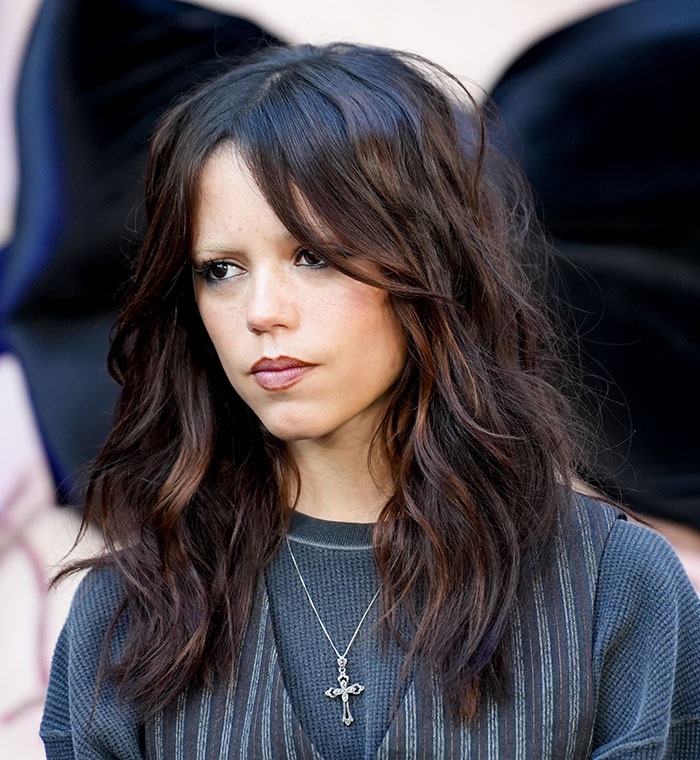 Jenna Ortega with serious expression and dark wavy hair, showing concern at Wednesday cast event. Jenna Ortega with serious expression and dark wavy hair, showing concern at Wednesday cast event.