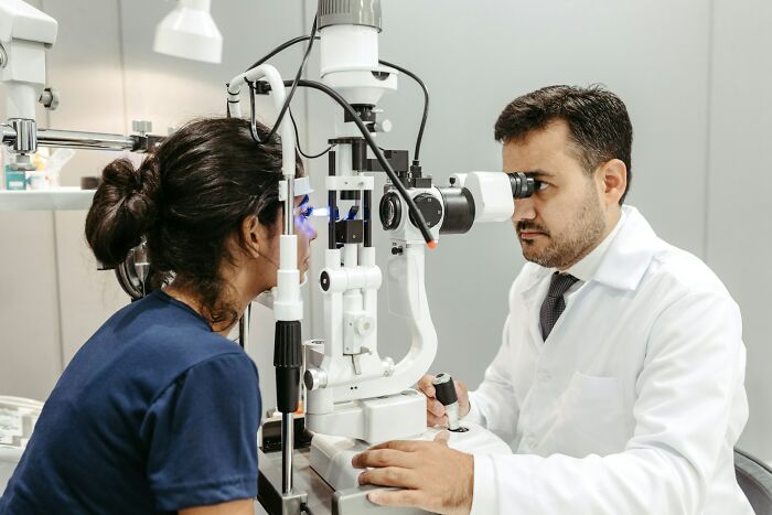 Doctor performing eye exam on patient using specialized medical equipment in clinical setting, showcasing work secrets.