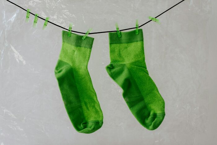 Two green socks hanging on a clothesline with clothespins, illustrating surprising habits discovered after moving in.