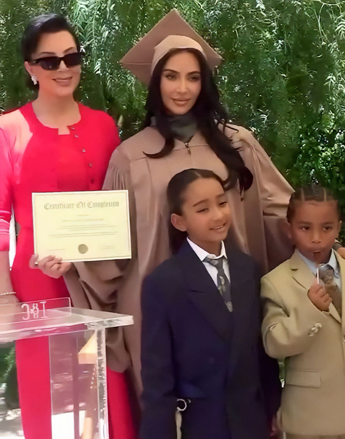 Kim Kardashian in graduation gown with family at outdoor event, highlighting pathological liars theme.