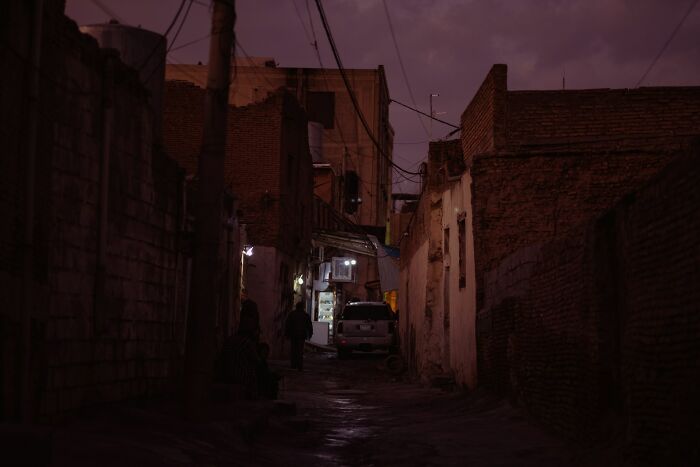 Dimly lit narrow alley at dusk with people walking, capturing the atmosphere of craziest coincidences people experienced.