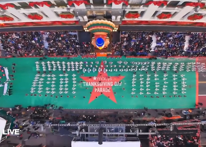 Aerial view of Macy’s Thanksgiving Day Parade with marching band and large crowd during the famous holiday event.