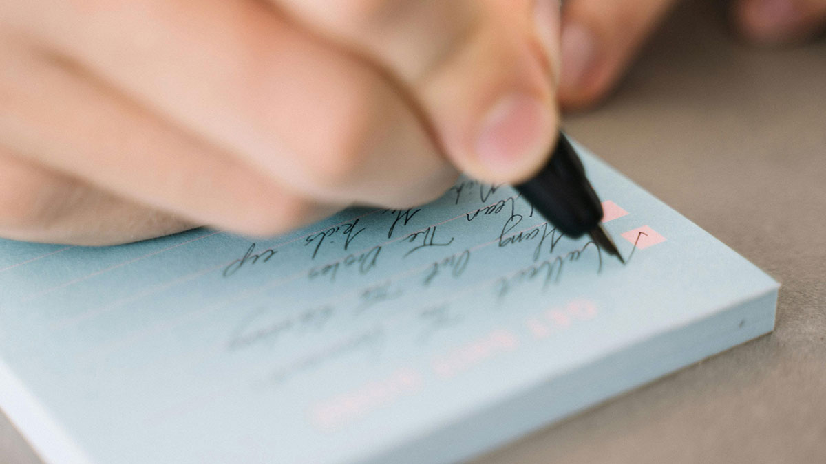 Close-up of a person writing on a checklist, sharing life hacks for better organization and productivity.
