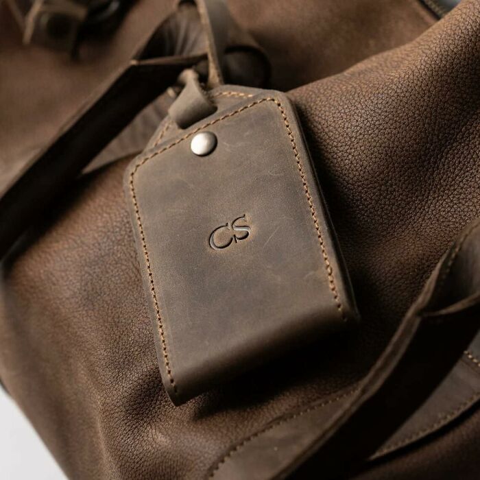 Close-up of a brown leather bag with a matching leather luggage tag, a stylish gift for people impossible to shop for.