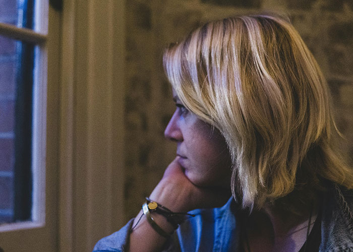 Teen girl looking thoughtfully out a window, capturing man’s reaction to teen daughter’s relationship concerns.