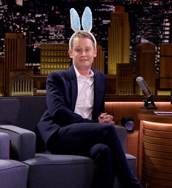Macaulay Culkin wearing bunny ears and a suit while sitting on a talk show set during an interview. Macaulay Culkin wearing bunny ears and a suit while sitting on a talk show set during an interview.