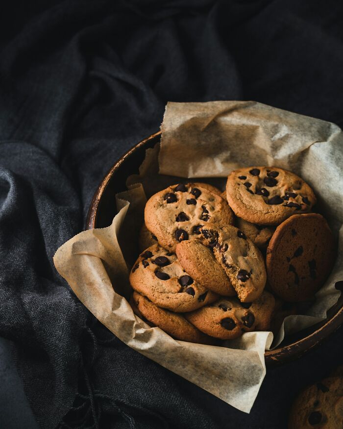 Basket of chocolate chip cookies on parchment paper, highlighting positive stereotypes about various countries and their cuisine.