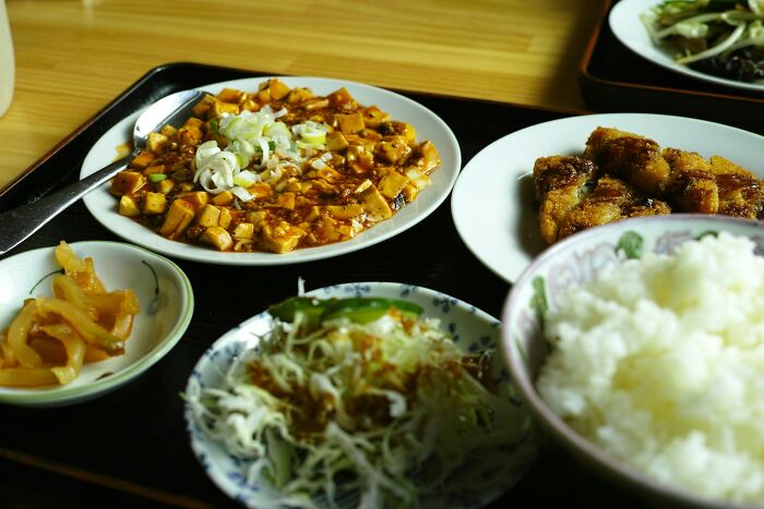 Assorted home-cooked dishes including tofu, rice, and vegetables on a wooden table, showcasing common cooking mistakes.