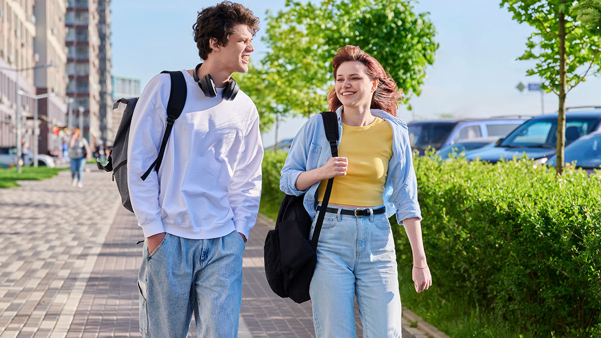 Young man and woman walking outdoors, appearing to have a lively conversation during a loyalty test moment.