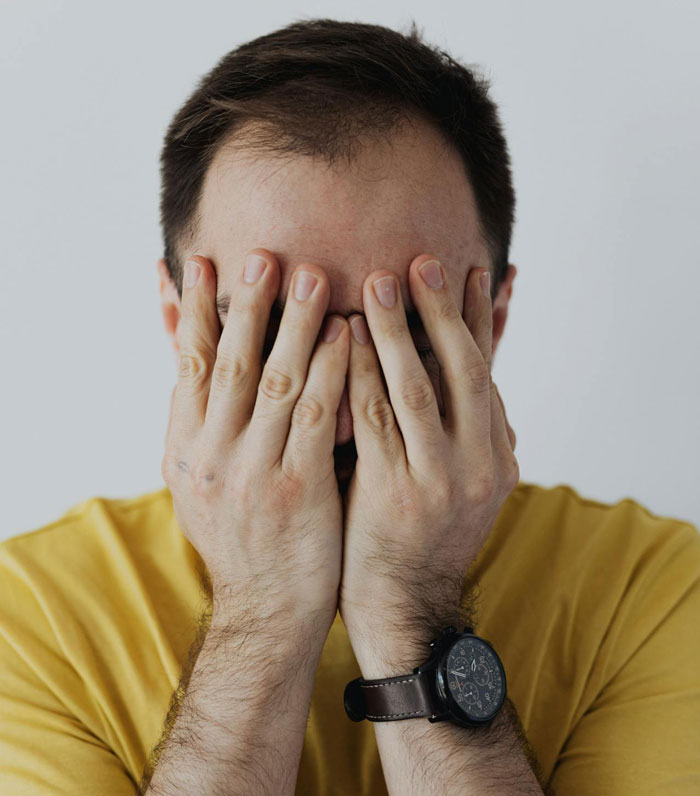 Man in yellow shirt covering face with hands showing frustration in family surprise Christmas story context. Man in yellow shirt covering face with hands showing frustration in family surprise Christmas story context.