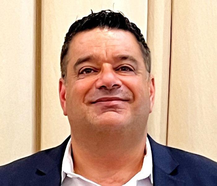 Middle-aged man in a dark suit smiling against a beige background related to Campbell's executive leaked audio on soup ingredients. Middle-aged man in a dark suit smiling against a beige background related to Campbell's executive leaked audio on soup ingredients.