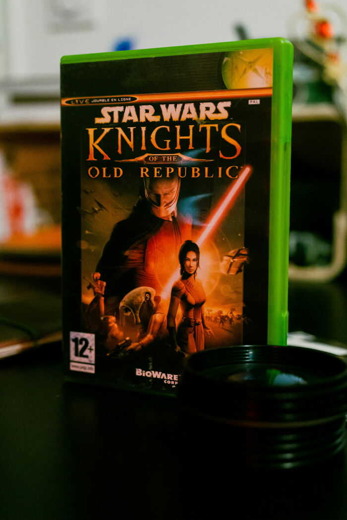 Star Wars Knights of the Old Republic game case on a table with a green border and sci-fi characters on cover. Star Wars Knights of the Old Republic game case on a table with a green border and sci-fi characters on cover.