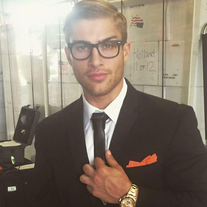 Young man with glasses wearing a suit and tie, posing confidently, linked to viral sensation called the next Brad Pitt. Young man with glasses wearing a suit and tie, posing confidently, linked to viral sensation called the next Brad Pitt.