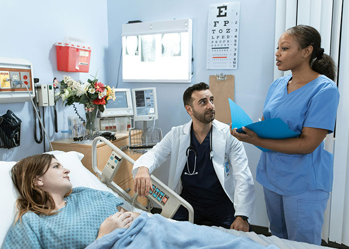 Doctor and nurse discussing patient care in hospital room, highlighting medical malpractice lawyer insights on everyday dangers.