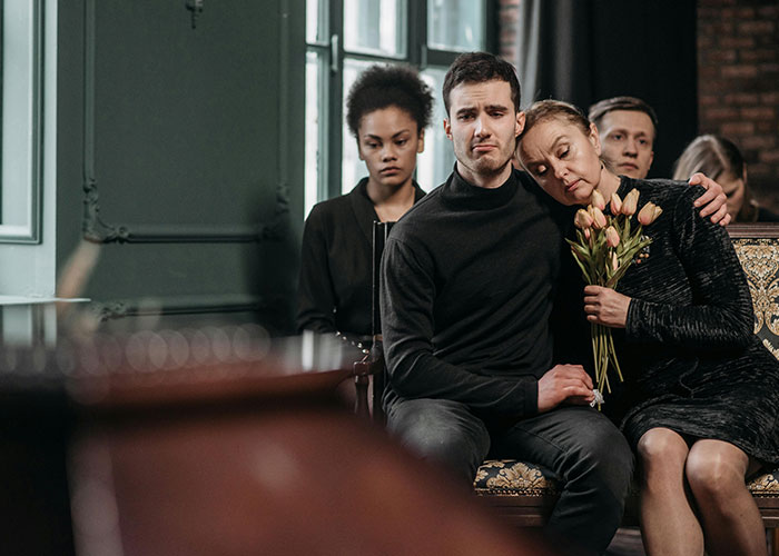 Mourners sitting together showing grief at a funeral, related to medical malpractice lawyer facts about dangers in life.