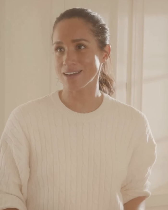 Meghan Markle in a casual white sweater, smiling indoors with warm natural light during a Thanksgiving turkey event. Meghan Markle in a casual white sweater, smiling indoors with warm natural light during a Thanksgiving turkey event.