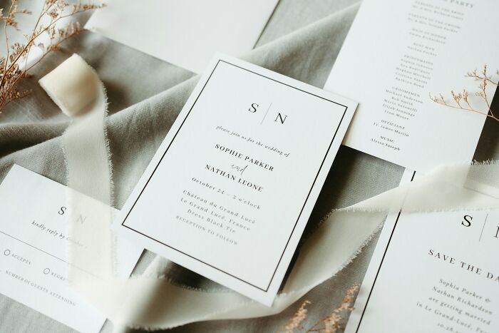 Wedding invitation cards and decor arranged on a gray fabric background illustrating signs of unfaithful partners.