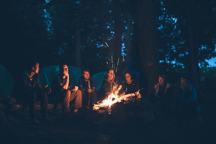 Group of people sitting around a campfire at night, highlighting moments when folks wanted to say something funny to loved ones.