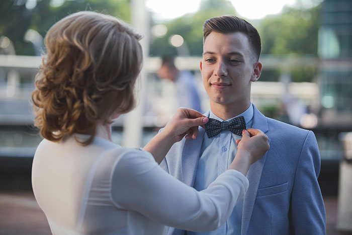 Mother adjusts son’s bow tie on wedding day as son looks on appalled by mom’s behavior during his big event Mother adjusts son’s bow tie on wedding day as son looks on appalled by mom’s behavior during his big event