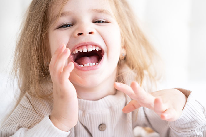 Young child laughing with mouth open and hands raised, illustrating a mildly disturbing fact concept in an innocent way.