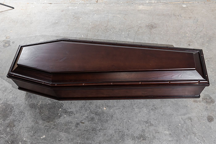 Dark wooden coffin on a concrete floor illustrating a mildly disturbing fact concept with eerie and unsettling tones.