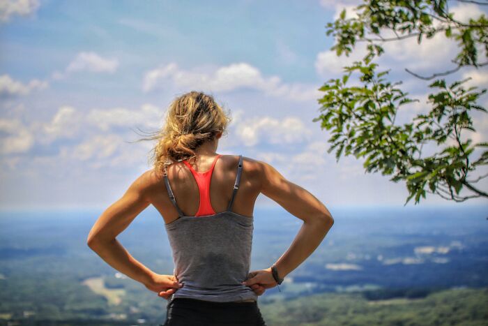 Woman standing on a mountain edge looking over the horizon, reflecting on real-life horror story experiences outdoors.