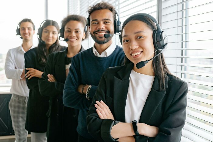 Diverse call center workers smiling and wearing headsets, showcasing hilarious and inventive ways workers got away with breaking rules.