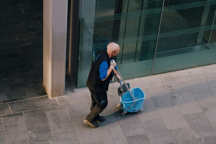Worker using a mop bucket on wheels, demonstrating inventive ways employees got away with breaking rules at work.