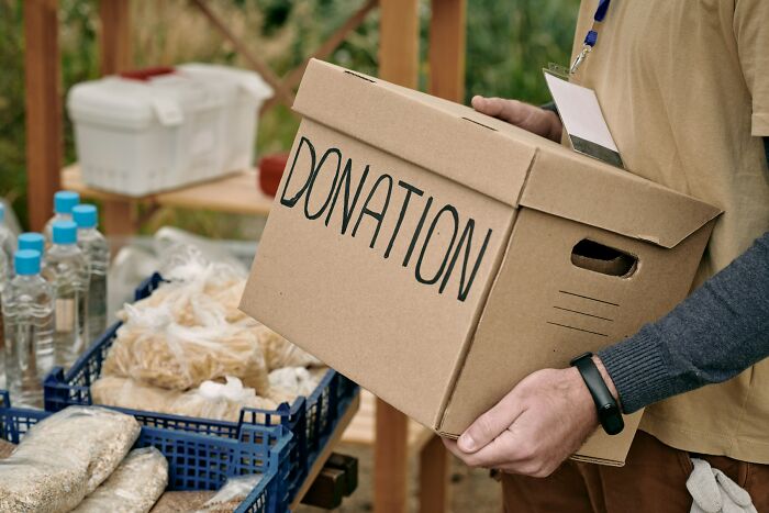 Person holding a donation box near packed food items, depicting inventive ways workers got away with breaking rules.