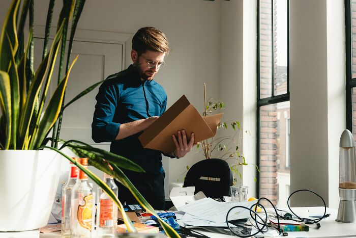 Man in blue shirt reviewing documents at cluttered desk in an office, illustrating inventive ways workers got away with breaking rules