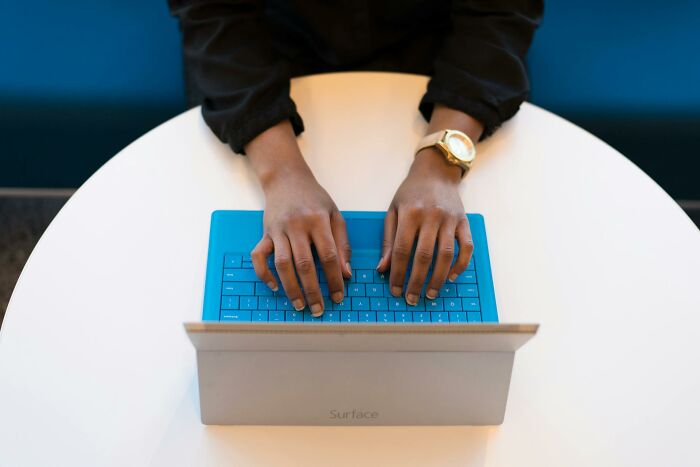 Person typing on a laptop at a round table, illustrating inventive ways workers got away with breaking rules.