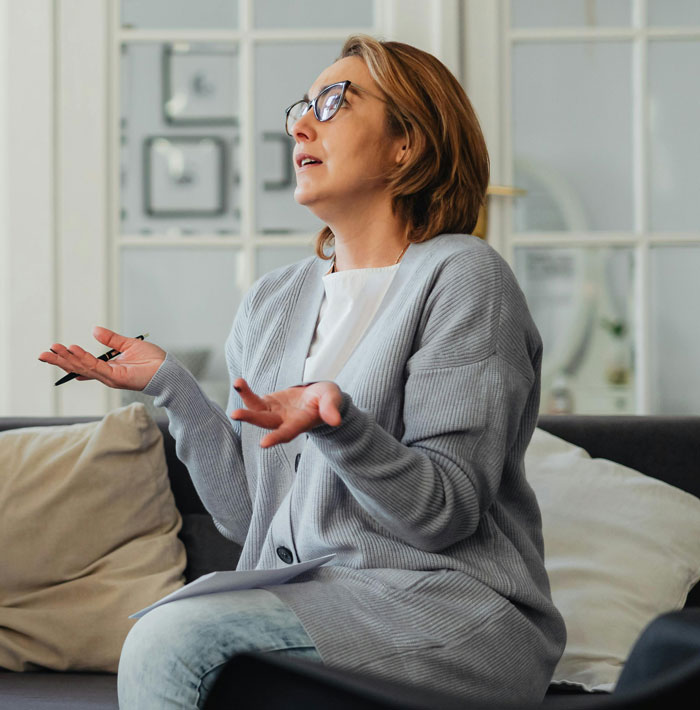 Woman in gray cardigan expressing frustration during a therapy session about trust and privacy issues.