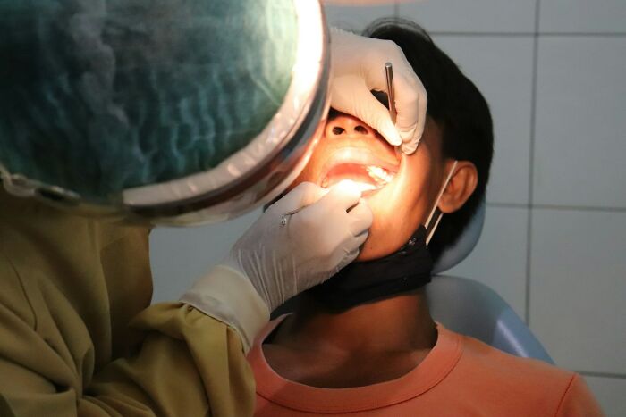 Dentist examining patient’s mouth with tools and bright light revealing wildest patient horror stories memories.